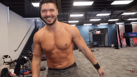 a shirtless man with a beard is smiling in a gym