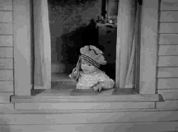 a black and white photo of a little girl looking out of a window