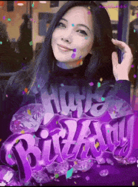 a woman is standing in front of a purple sign that says happy birthday