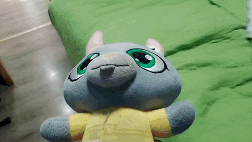 a stuffed animal with green eyes is sitting on a bed