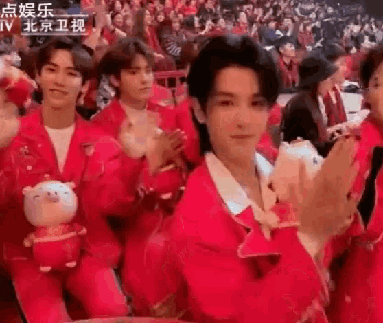 a group of people in red jackets are sitting in a stadium .