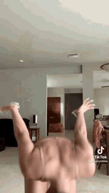 a woman is doing a handstand in a living room in a tiktok video .