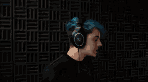 a man with blue hair is wearing headphones and making a funny face .