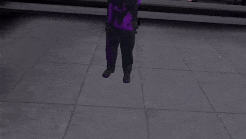 a man in a purple shirt is standing with his arms outstretched in a dark room