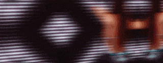 a blurry picture of a person standing in front of a window with blinds on it .