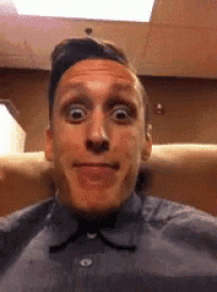 a man in a blue shirt is making a funny face while sitting in a chair .