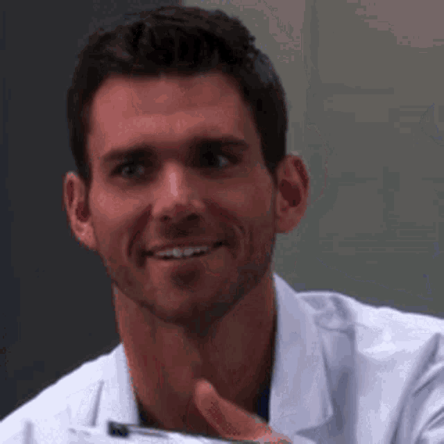 a man in a white shirt is smiling while holding a clipboard .