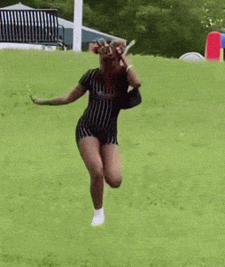 a woman is running down a grassy hill .