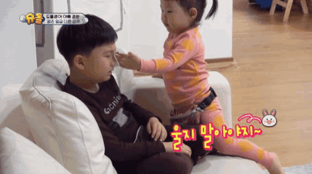 a little girl putting something on a boy 's nose with korean writing on it