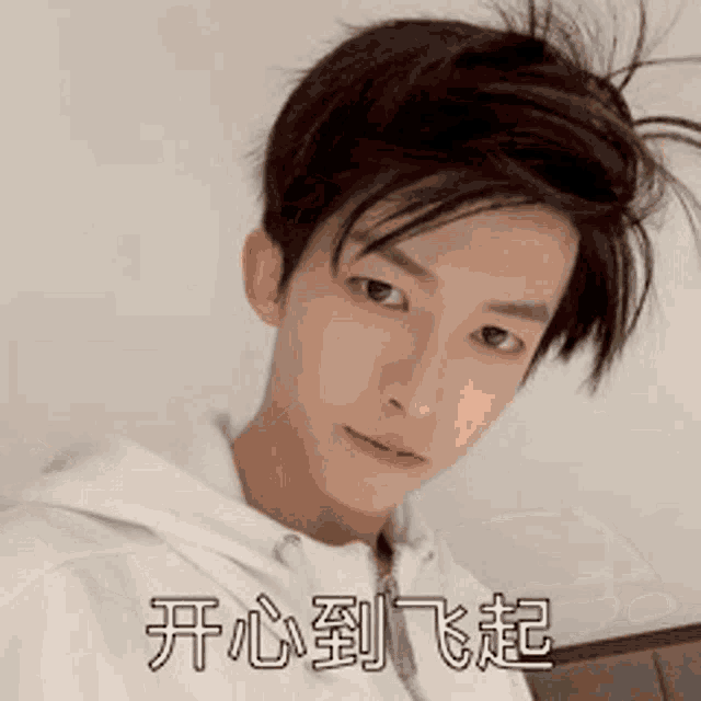 a young man with messy hair is wearing a white hoodie and has chinese writing on his face .
