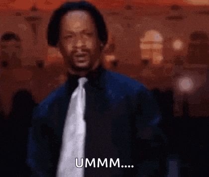 a man in a suit and tie is standing in front of a crowd and saying ummm .
