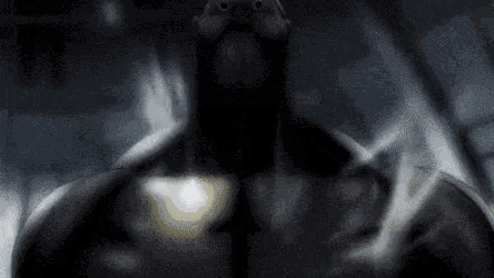 a man with a beard is standing in the dark with his hands in the air .