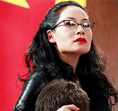 a woman wearing glasses and red lips is holding a man 's head