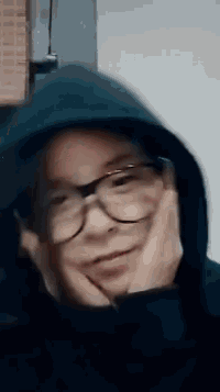 a person wearing glasses and a hoodie is making a face .