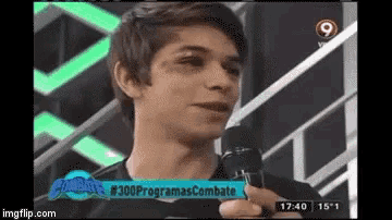 a young man is talking into a microphone on a tv show
