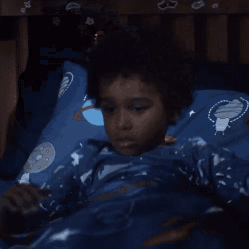 a young boy in a blue shirt with whales on it is holding his nose