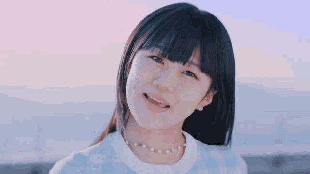 a close up of a girl wearing a blue shirt and a necklace