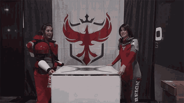 two women stand in front of a flag that says reign on it