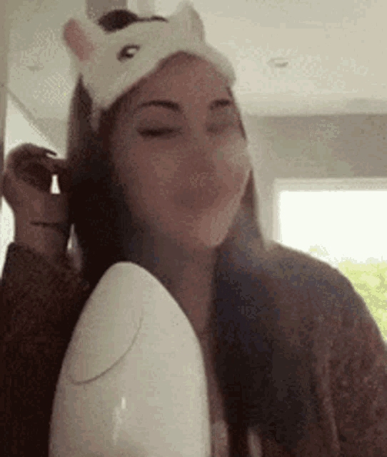 a woman wearing a unicorn headband is using a steamer to clean her face .