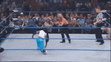 a referee stands in a wrestling ring watching a wrestler