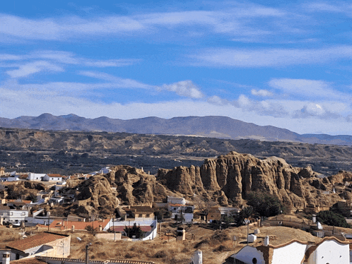 a landscape with mountains in the background and a few buildings in the foreground