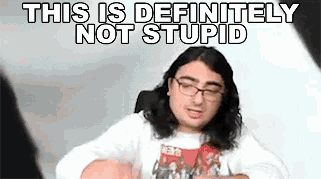 a man with long hair and glasses is sitting in front of a white background .