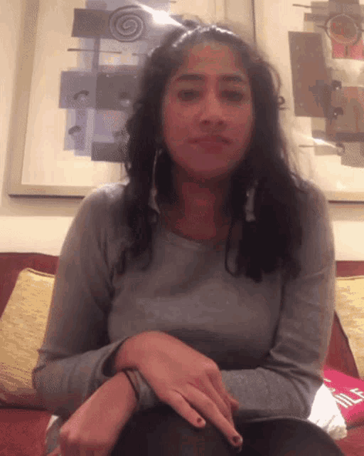 a woman sitting on a couch with a picture behind her that says ' a ' on it