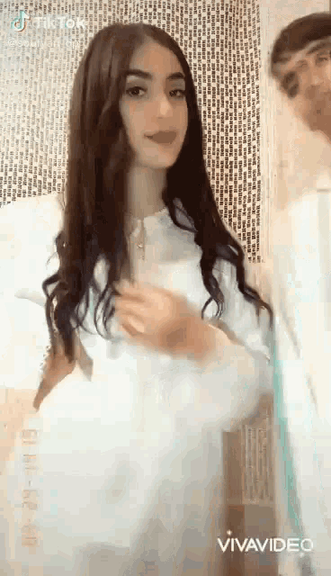a woman is standing next to a man in a white dress .