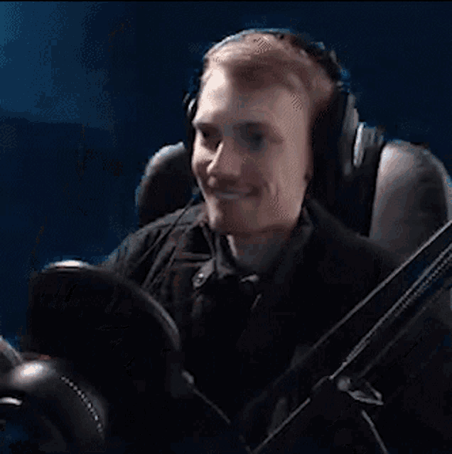 a man wearing headphones is sitting in a chair with a microphone .