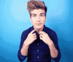 a young man in a blue shirt is adjusting his shirt collar