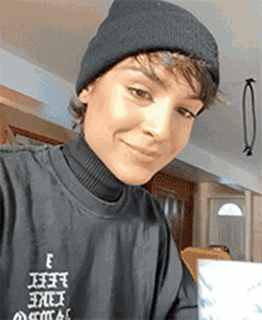 a woman wearing a black beanie and a black t-shirt with the letter e on it .