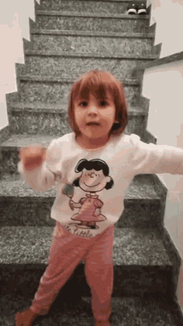 a little girl is standing on a set of stairs wearing a snoopy sweater
