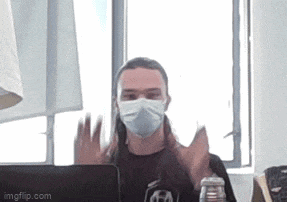 a man wearing a mask is sitting at a desk in front of a laptop computer .