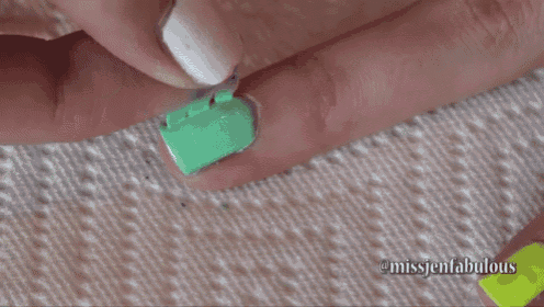 a close up of a person 's nails with a green sticker on them
