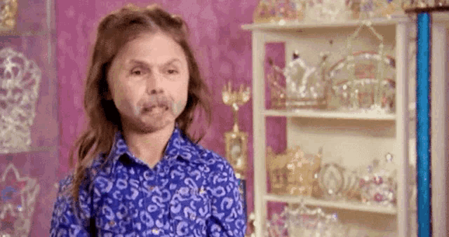 a little girl with long hair is wearing a blue shirt with a leopard print .