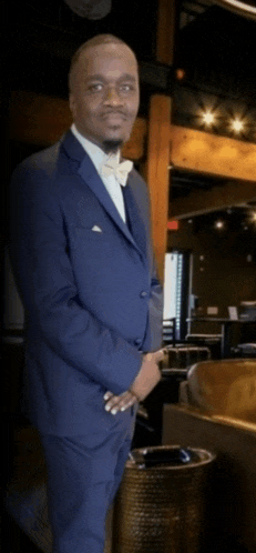 a man in a suit and bow tie is standing in a room