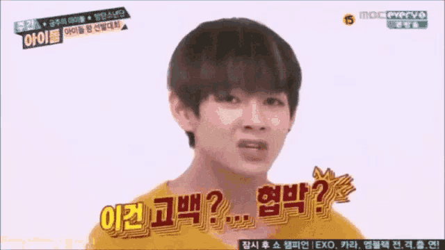 a young man in a yellow shirt is making a funny face while talking in a foreign language .