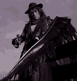 a man in a cowboy hat is holding a gun and a large sword