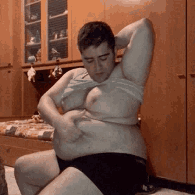 a man with a very large belly is sitting on the floor .