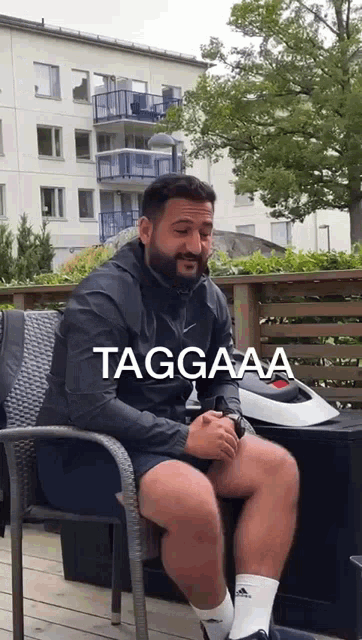 a man with a beard is sitting in a chair with the words taggaaa on the bottom