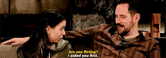 a man and a woman are sitting on a couch and the man says " are you flirting "