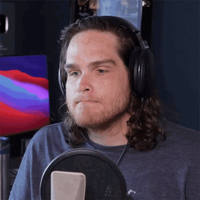 a man with long hair wearing headphones looks at the camera