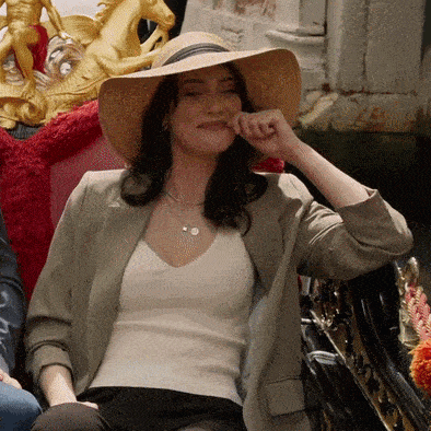 a woman wearing a hat and a necklace is sitting in a chair