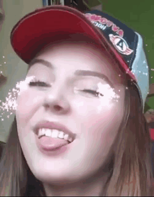 a girl wearing a hat is sticking her tongue out .