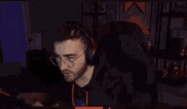 a man wearing headphones and glasses is sitting in front of a computer screen .