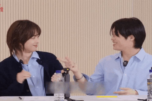 a couple of people sitting at a table with bottles of water