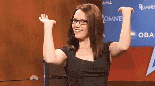 a woman wearing glasses is raising her arms in the air