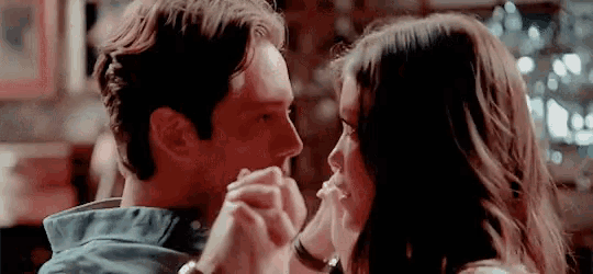 a man and a woman are holding hands and looking into each other 's eyes
