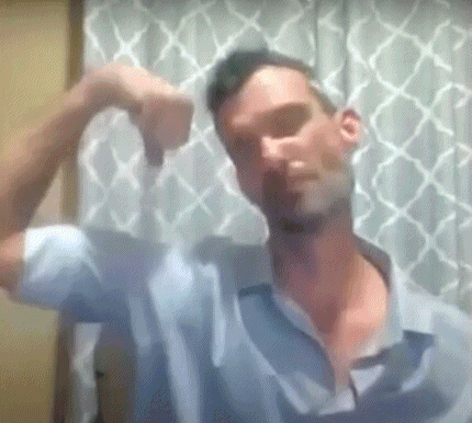 a man in a blue shirt is flexing his muscles and giving a thumbs down .