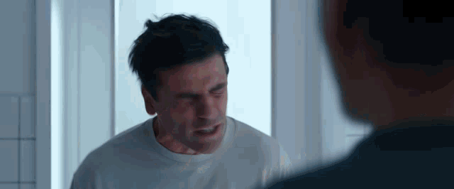 a man is looking at himself in the mirror and making a funny face .